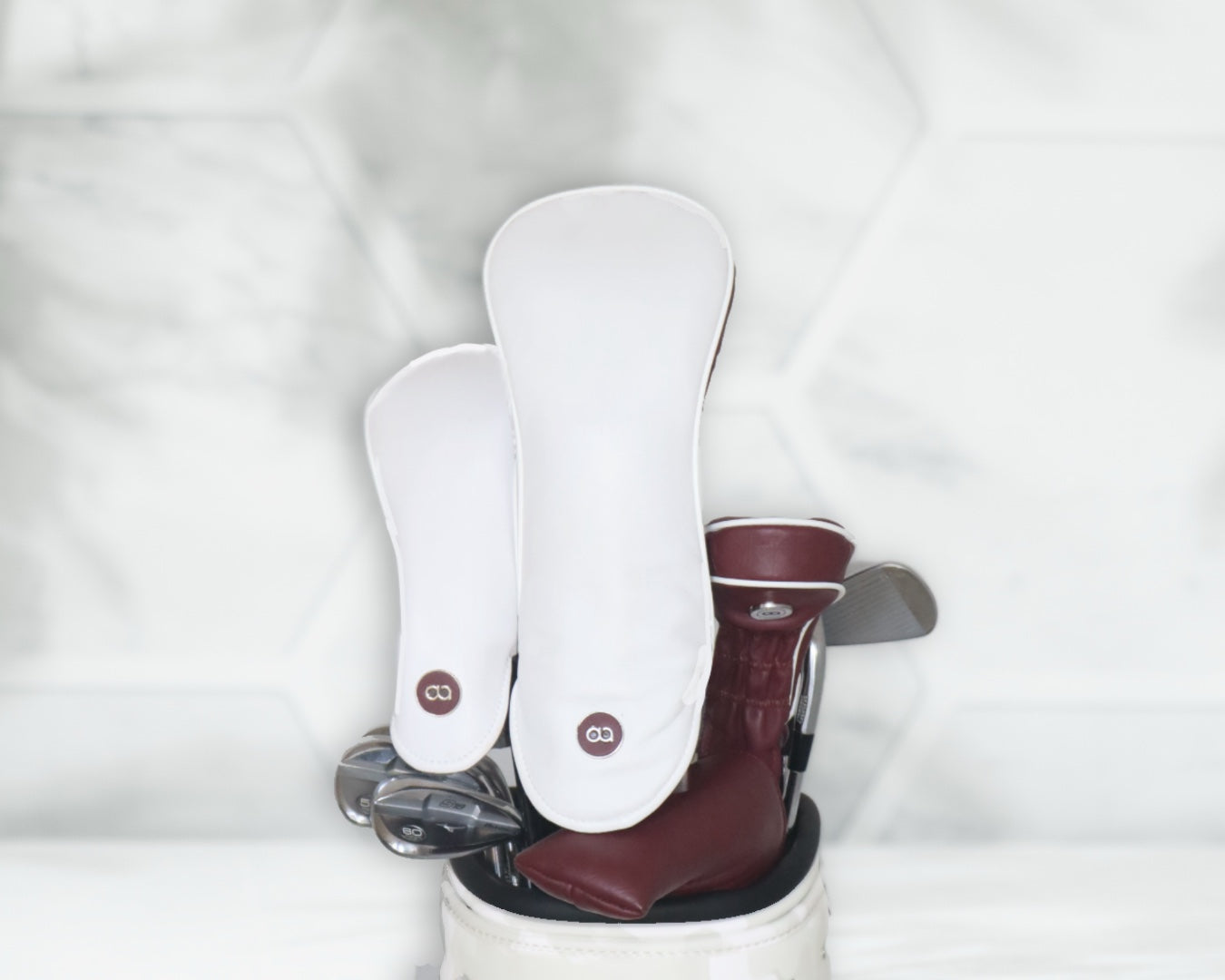 White and burgundy leather golf club headcover set by David Alexander against a white floral background.