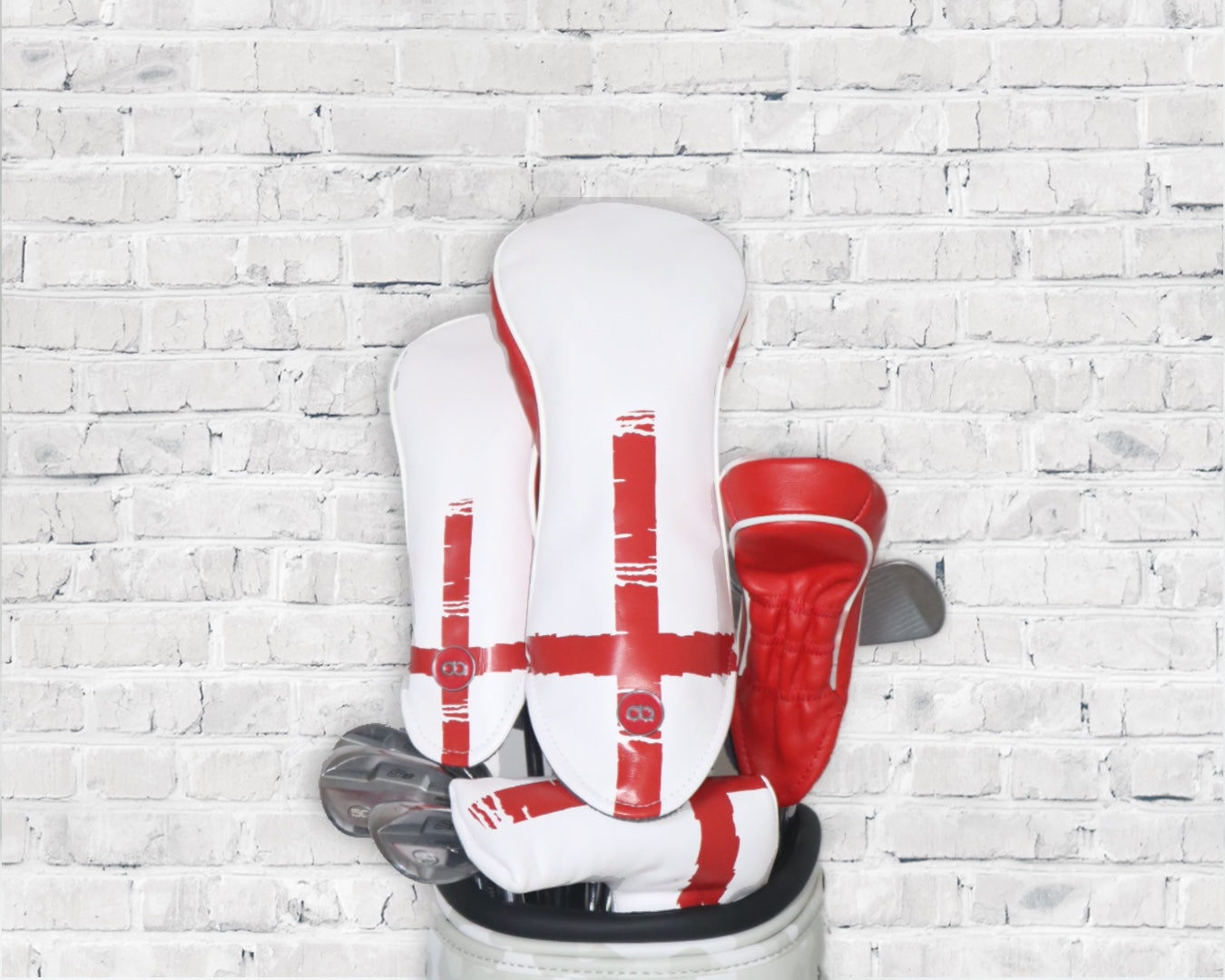 White and red England leather golf club headcover set by David Alexander against a white wall background.