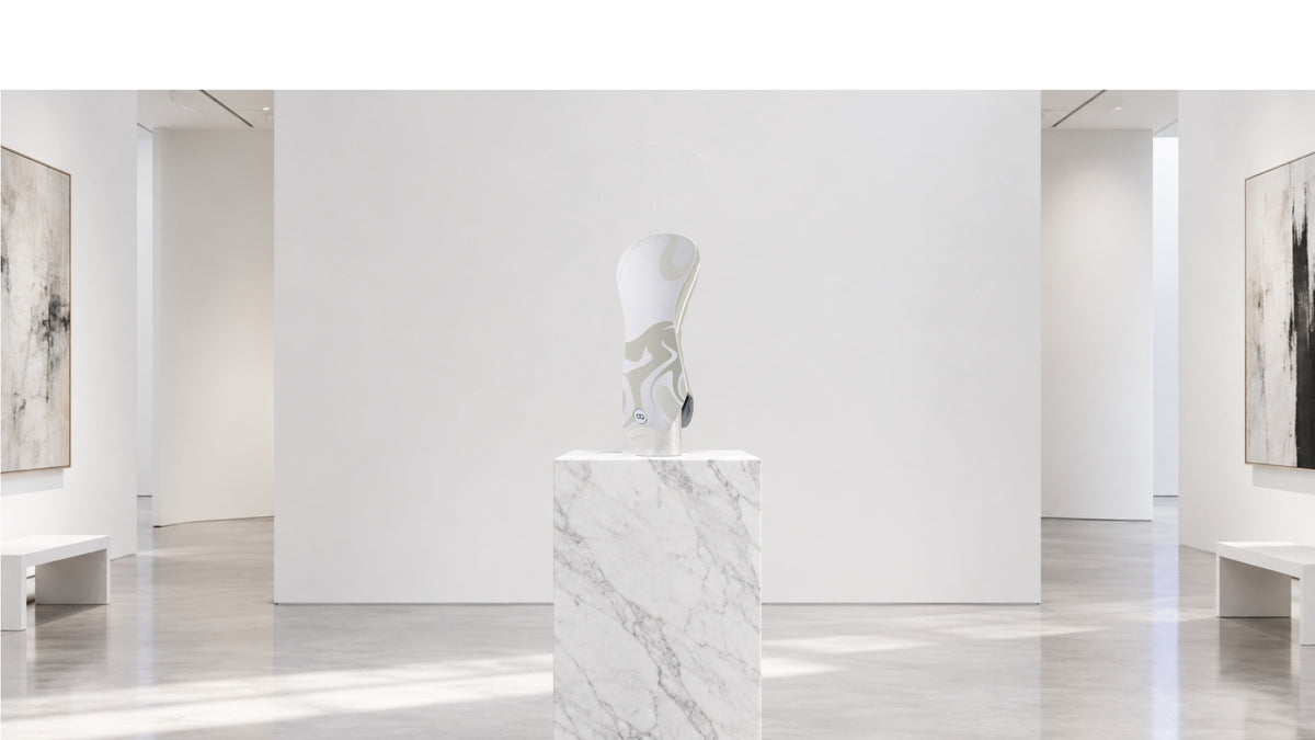 A white leather golf club headcover with an abstract design by David Alexander sitting on a plinth in an art gallery.
