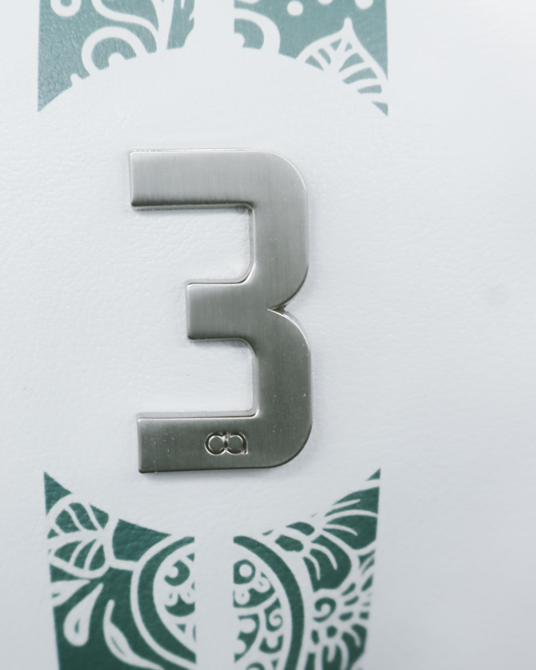 Chrome insignia on white and teal green leather headcover by David Alexander