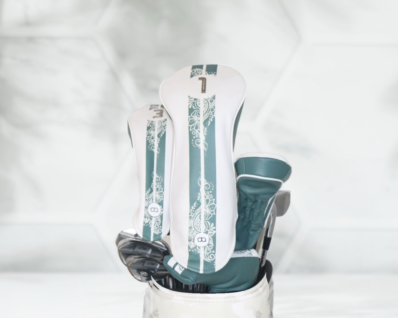 White and green henna leather golf club headcover set by David Alexander against a white floral background.