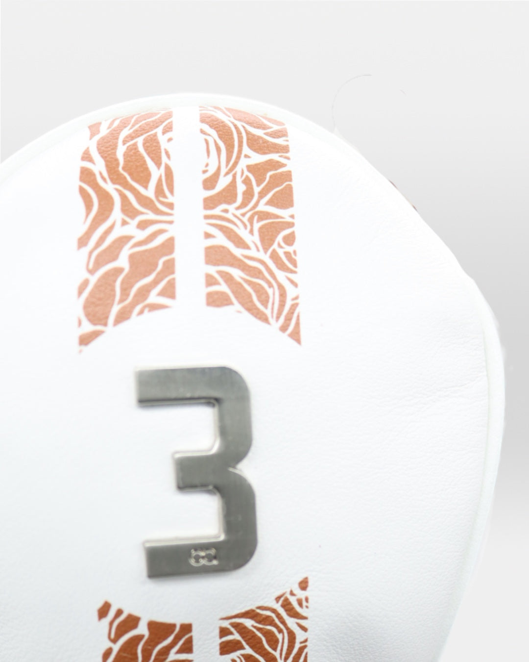 Chrome insignia on white and bronze leather headcover by David Alexander