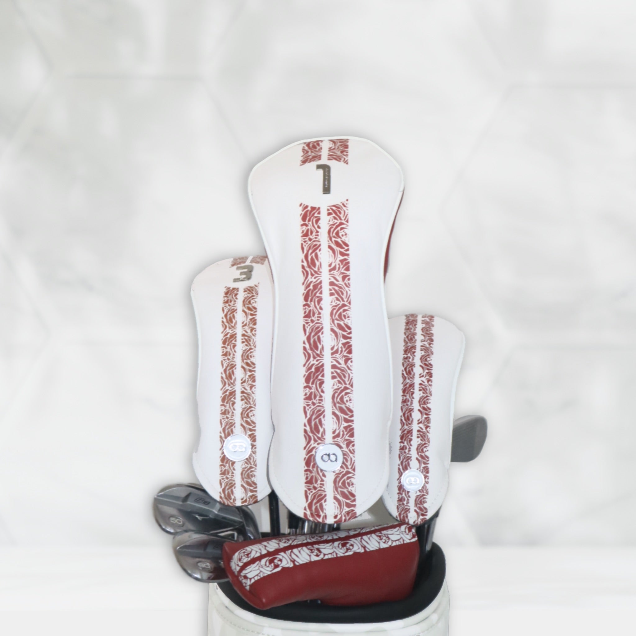 A set of scarlet, bronze and white leather golf club headcovers with a rose stripe design by David Alexander