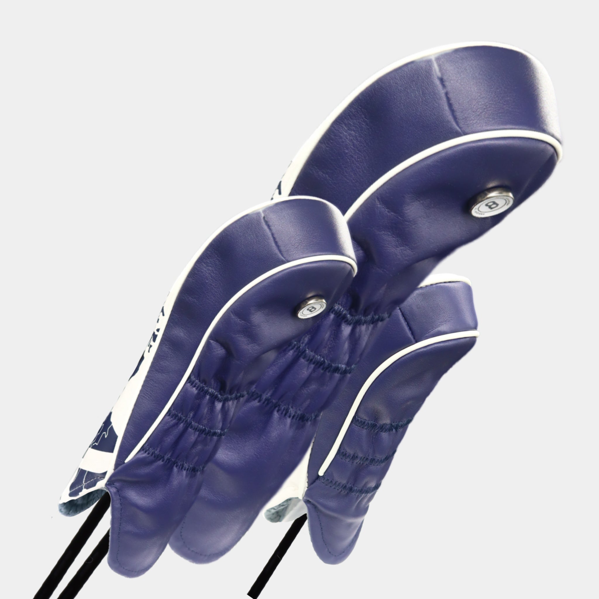 A set of white and blue Scotland leather headcovers against a white wall