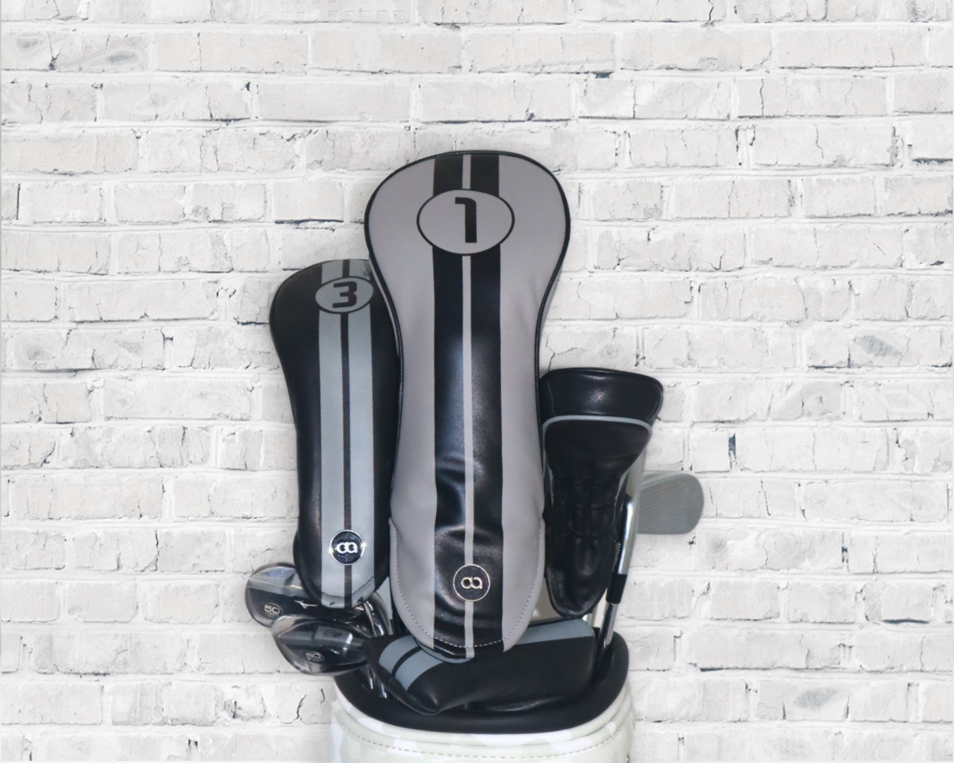 Grey and black Racing Line leather golf club headcover set by David Alexander against a white wall background.