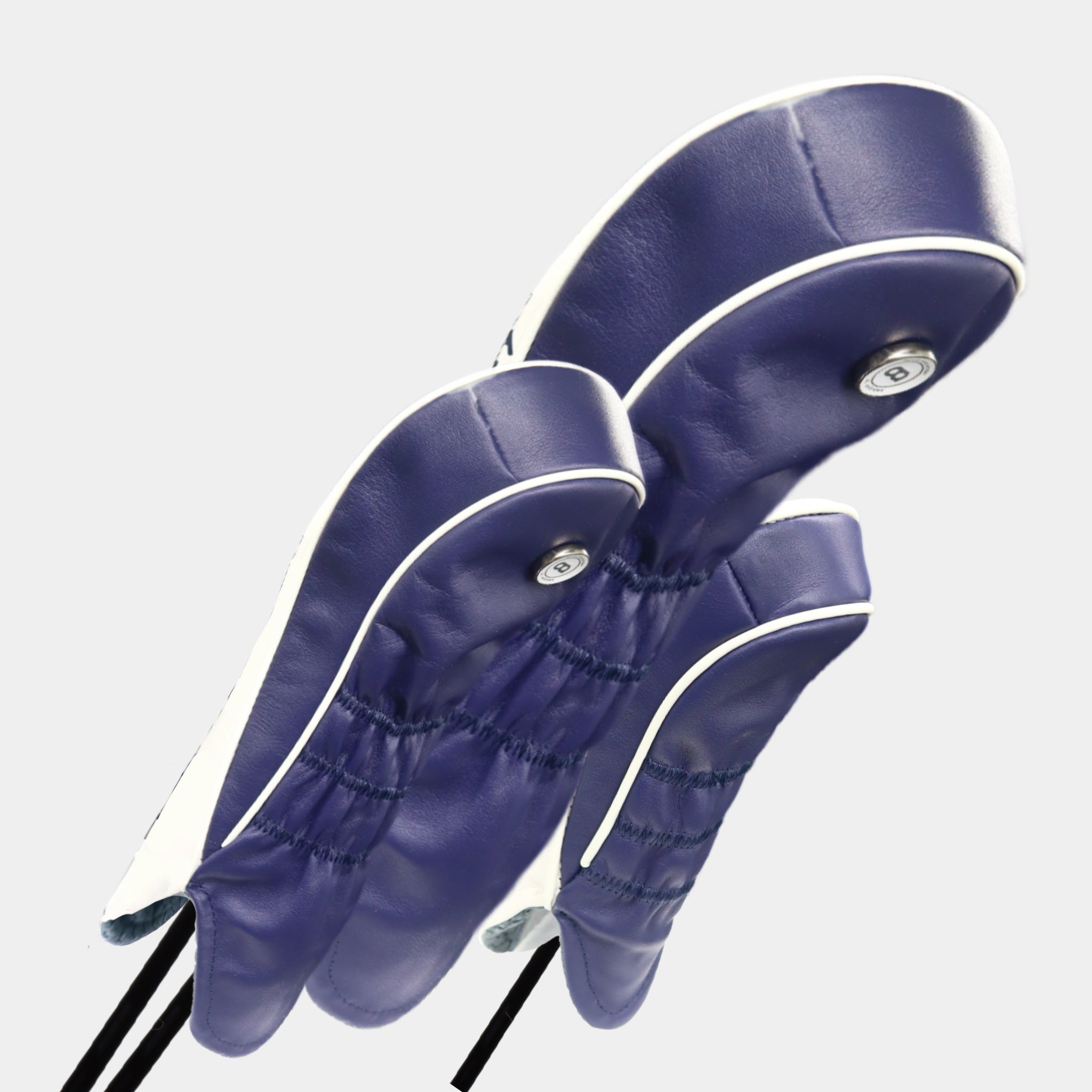 A set of white and blue Scotland leather headcovers against a white wall