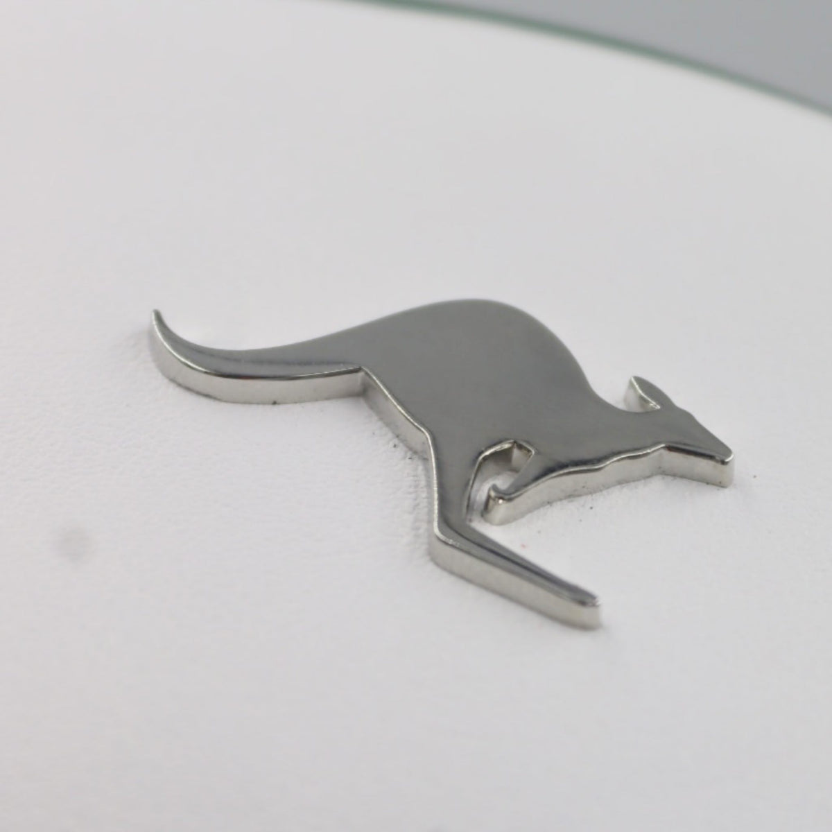 A polished chrome metal kangaroo emblem shown on a white leather Australia golf club headcover