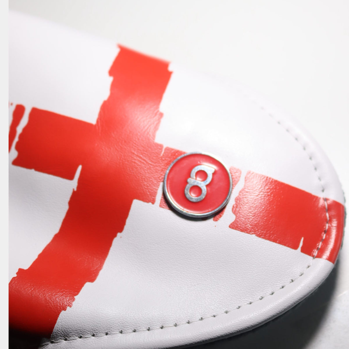 Close-up of a white leather golf club headcover with a bold red St. George's cross design and a circular red badge featuring a David Alexander Golf logo.