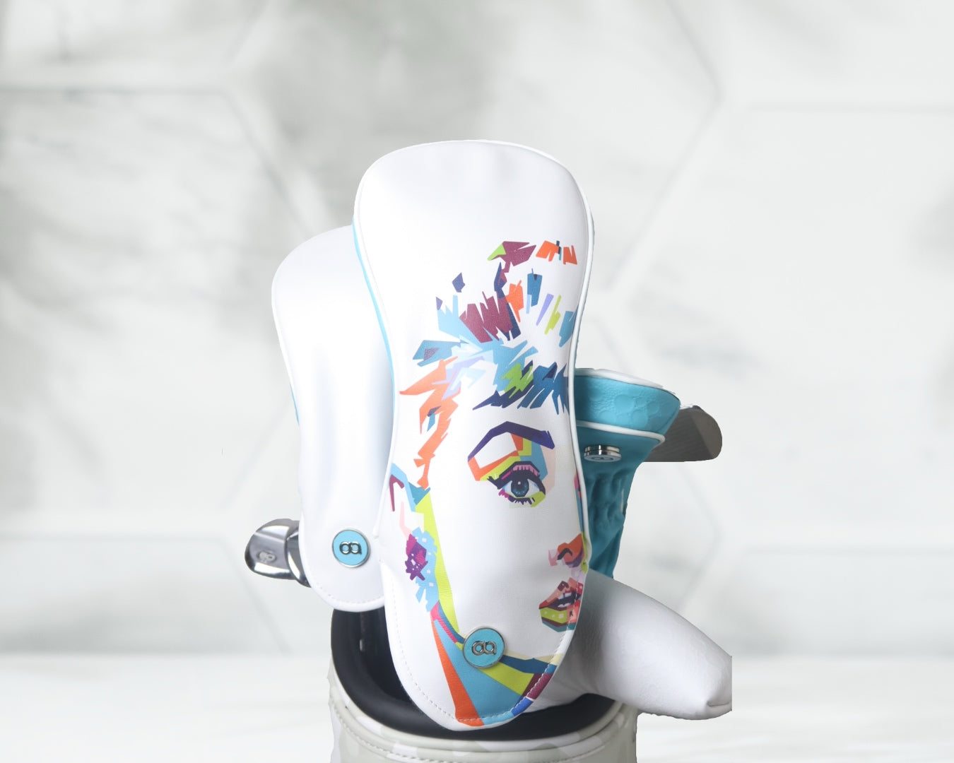 White and aqua blue leather golf club headcover set with Audrey Hepburn against a white floral background.