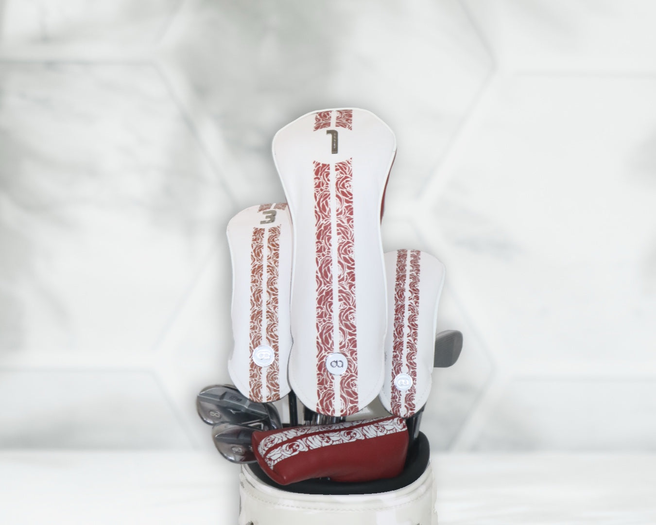 White and red leather golf club headcover set by David Alexander against a white floral background.