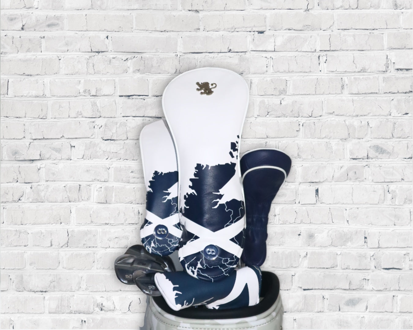 White and blue Scotland leather golf club headcover set by David Alexander against a white wall background.