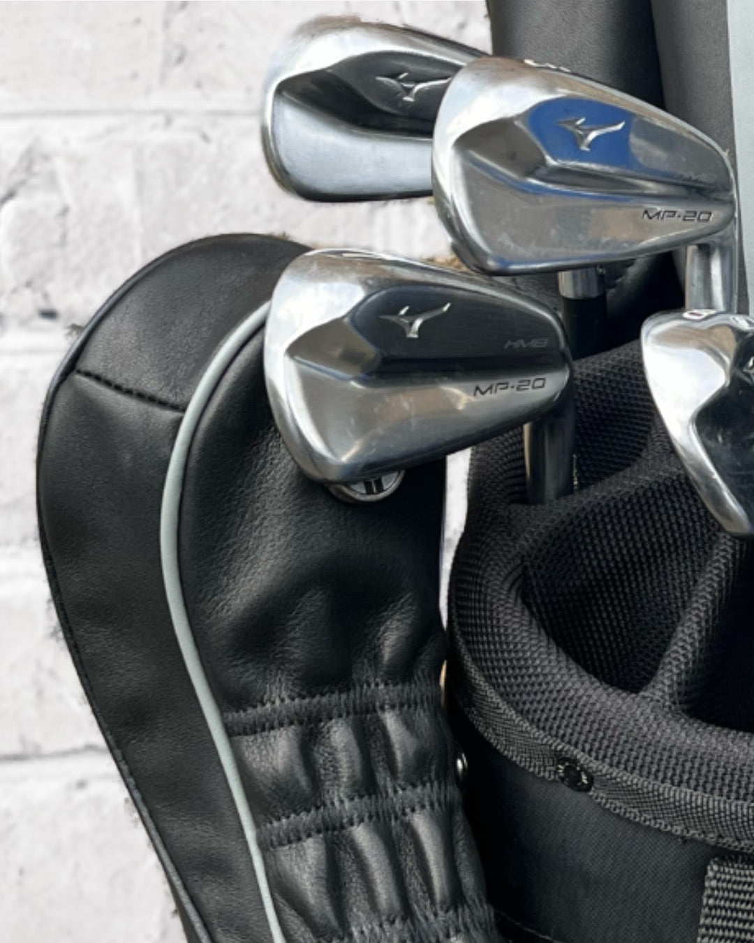 Black magnetic headcover attached to golf clubs.