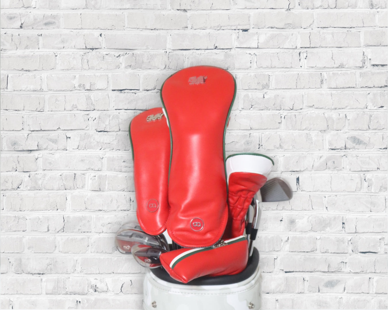 Red Wales leather golf club headcover set by David Alexander against a white wall background.