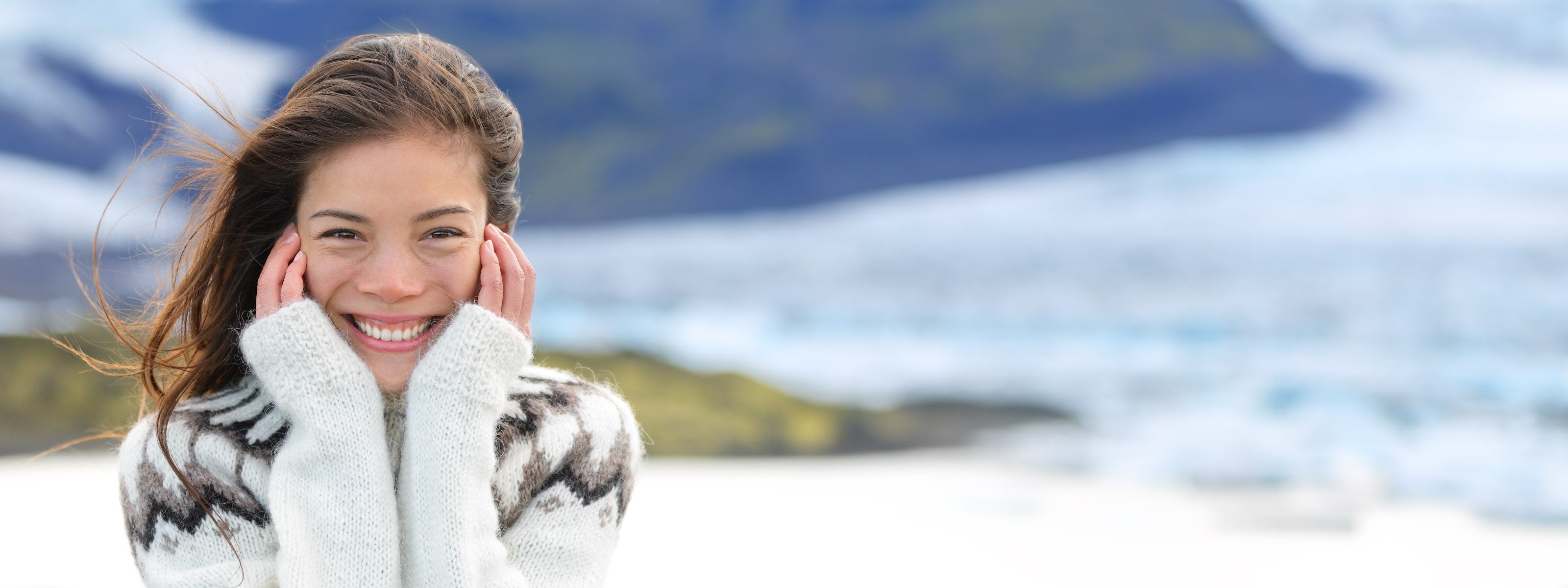 Woman in a winter coat with a snowy landscape and mountains in the background